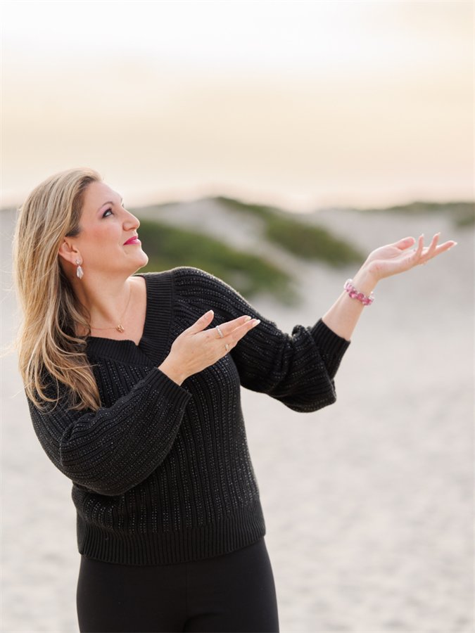 Amanda Robinson on the beach, hands raised