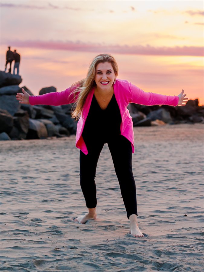 Amanda with open arms on the beach at sunset