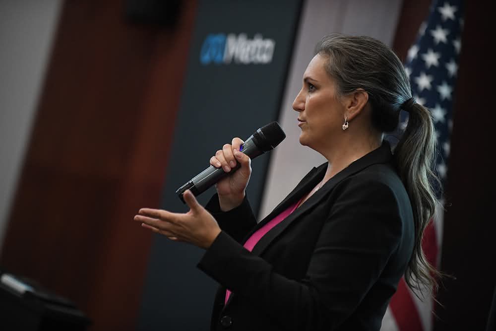 Amanda Robinson speaking into a microphone at a Meta training event